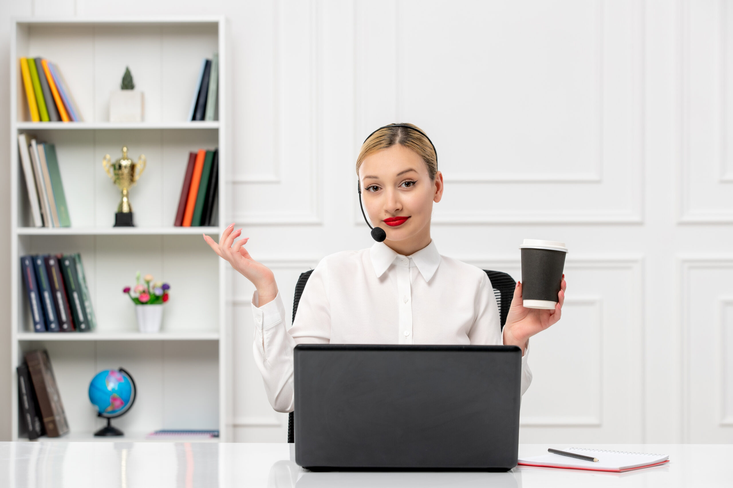 A young professional wearing a headset during a VoIP call, seated at a desk with a laptop and coffee, representing VoIP call quality in a modern workspace.
