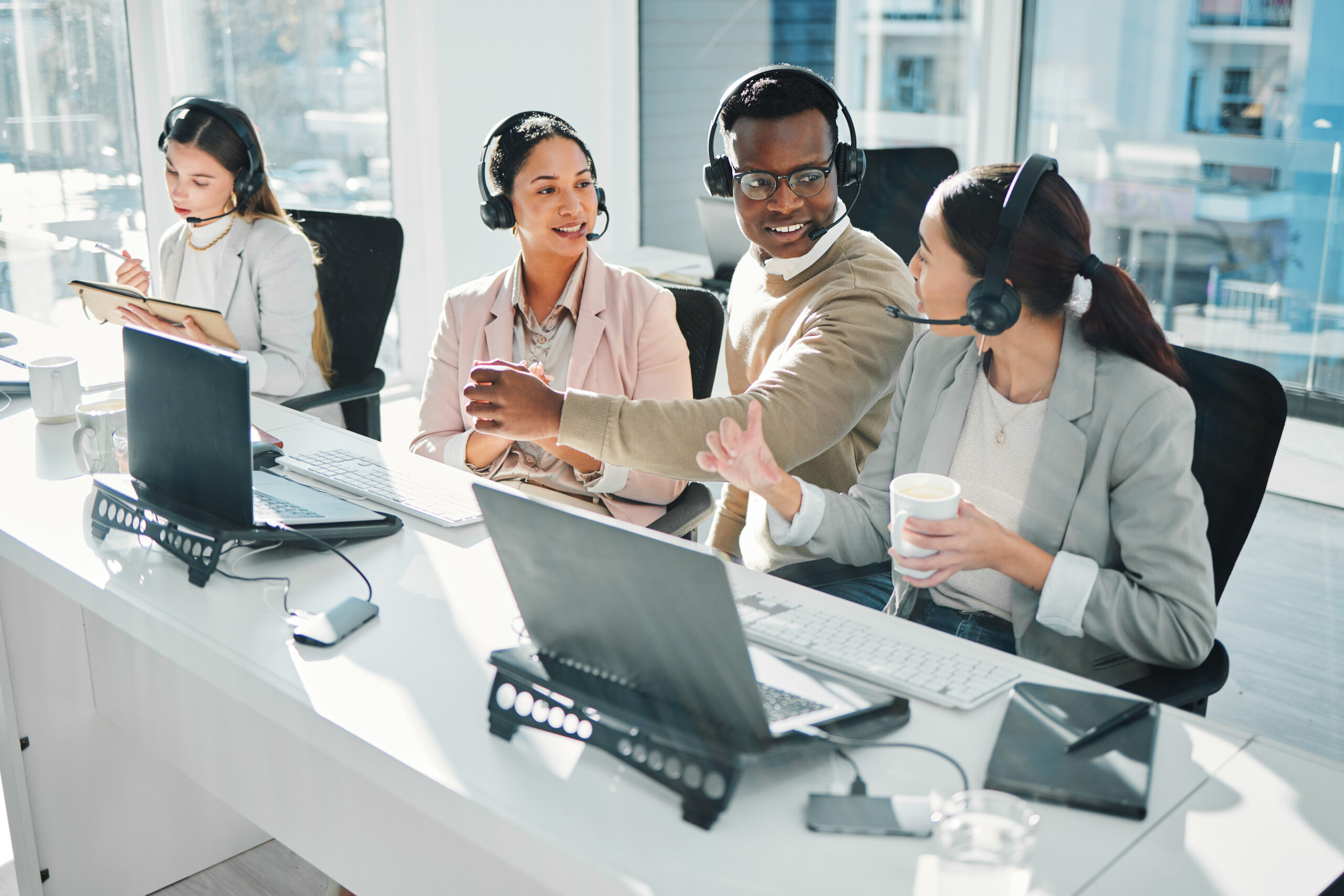 VoIP services team working with headsets and laptops in a modern office.